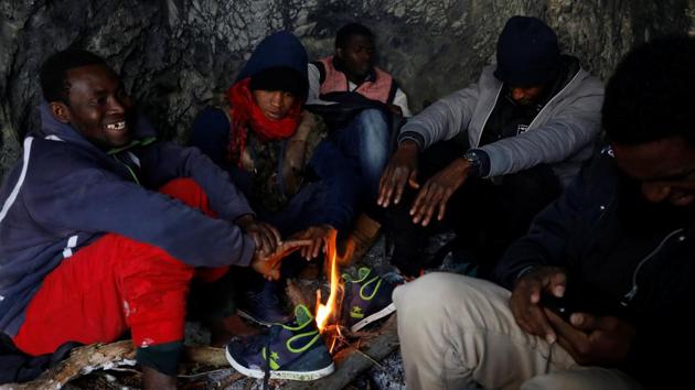 Kamarra, 28 (L), from Guinea and other migrants warm up by a fire in a cave after crossing part of the Alps. “I was imprisoned and tortured in Libya for many months. I was forced to work for free. Just look at my scars,” he said, lifting his clothes to show marks on his body. (Siegfried Modola / Reuters) Kamarra, 28 (L), from Guinea and other migrants warm up by a fire in a cave after crossing part of the Alps. “I was imprisoned and tortured in Libya for many months. I was forced to work for free. Just look at my scars,” he said, lifting his clothes to show marks on his body. (Siegfried Modola / Reuters)