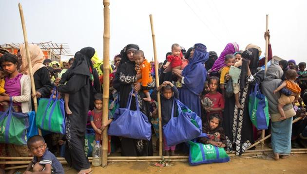Rohingya Muslim women with their children stand in a queue outside a food distribution centre at Balukhali refugee camp, 50 kilometres from, Cox's Bazar, Bangladesh.(AP Photo)