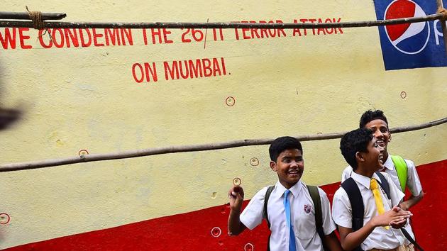 Schoolchildren walk past a wall pock-marked with bullet holes opposite the Nariman House. (Vijayanand Gupta/HT Photo) 