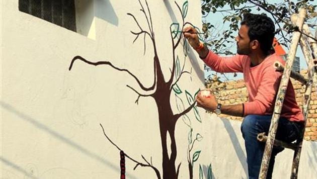 A volunteer paints walls in Kherla village of Nuh tehsil in Mewat district.