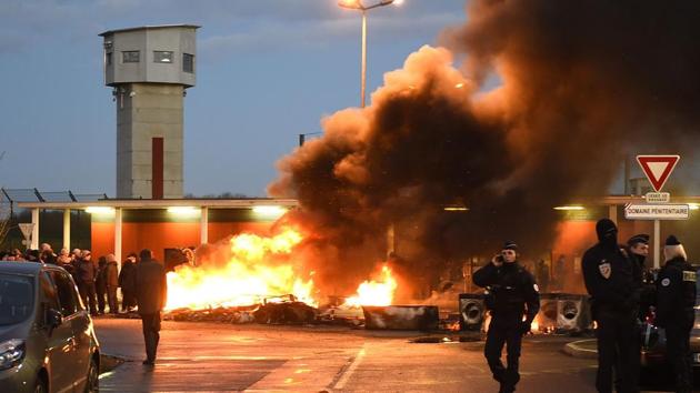 French police (R) stand near prison guards and burning wooden palettes as the guards block access to Vendin-le-Vieil prison on January 16, 2018 to demand tighter security after three officers were injured in an attack by a German terror convict last week. (AFP Photo) French police (R) stand near prison guards and burning wooden palettes as the guards block access to Vendin-le-Vieil prison on January 16, 2018 to demand tighter security after three officers were injured in an attack by a German terror convict last week. (AFP Photo)