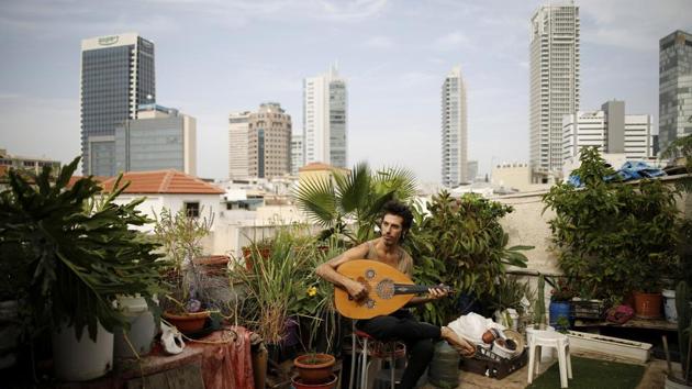 Musician Iyar Semel, 38, plays an oud on his rooftop garden, where he grows herbs and vegetables with his flatmates in Tel Aviv, Israel. Iyar planted an organic garden on his rooftop, with compost, vegetables, fruit trees and a shower. It all allows him to merge his ecological lifestyle with the restraints of urban space. (Corinna Kern / REUTERS)