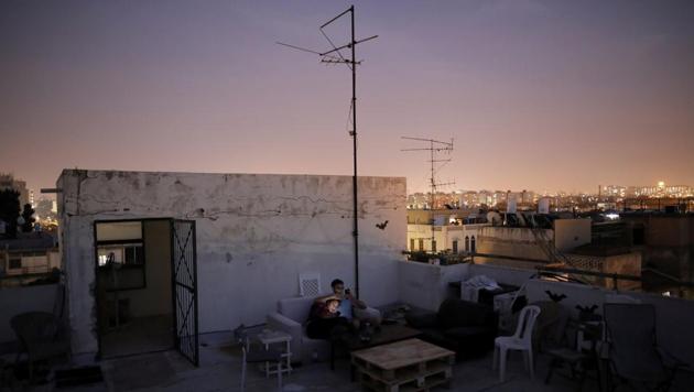 Hana Wimberly (L), 26, and Emanuel Cohen, 36, spend an evening on their roof in Tel Aviv. Hana turned her barren, cement rooftop into an outdoor salon with just a few mix matched chairs, a couch and a wooden table. "For more than anything it's a place for me to feel very connected to the city," she said. "Tel Aviv, as much as there is to do, going to a bar and spending 50 shekels ($15 USD) on a drink gets exhausting." (Corinna Kern / REUTERS)