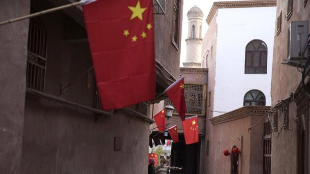 In this Nov. 4, 2017, photo, a child reacts to a stranger as adults chat along the corridor of the old city district where Chinese national flags are prominently hung in Kashgar in western China's Xinjiang region. (AP) In this Nov. 4, 2017, photo, a child reacts to a stranger as adults chat along the corridor of the old city district where Chinese national flags are prominently hung in Kashgar in western China's Xinjiang region. (AP)