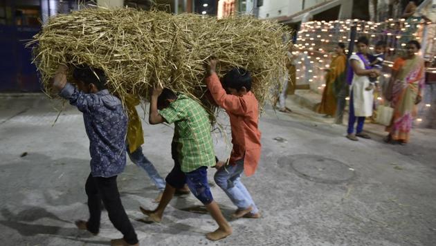 Children seen taking haystacks in preparation for Kichchu Haisodu bonfires. As evening set, festivities turned to the main attraction of the day with crowds thronging to balconies and lining streets to witness the leaps through fire. (Arijit Sen / HT Photo) Children seen taking haystacks in preparation for Kichchu Haisodu bonfires. As evening set, festivities turned to the main attraction of the day with crowds thronging to balconies and lining streets to witness the leaps through fire. (Arijit Sen / HT Photo)