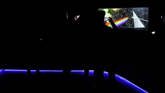 Silhouettes seen in front of a replica of the 'The Dark Side of the Moon' cover art. The exhibition was previously hosted at London’s Victoria and Albert Museum. (Andreas Solaro / AFP) Silhouettes seen in front of a replica of the 'The Dark Side of the Moon' cover art. The exhibition was previously hosted at London’s Victoria and Albert Museum. (Andreas Solaro / AFP)