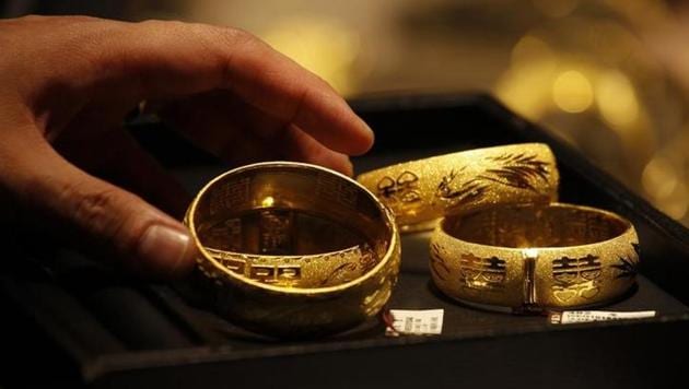 A shop attendant shows two pairs of 24K gold bracelets to a customer inside a jewellery store.(Reuters File Photo)