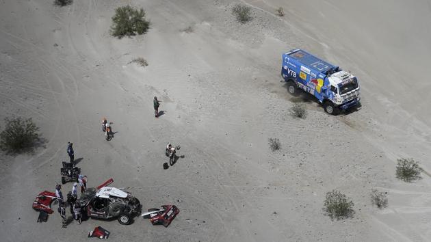 Russians Eduard Nikolaev and Evgeny Yakovlev, race their Kamaz as Mikko Hirvonen, of Finland, and co-driver Andreas Schulz, of Germany, work on their Mini during Stage 11 between Belen and Chilecito/Fiambala, Argentina. (Ricardo Mazalan / AP) 