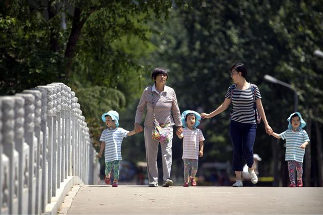 Women walk with children wearing matching hats as they cross a bridge at a public park on International Children's Day in Beijing. (AP File Photo) Women walk with children wearing matching hats as they cross a bridge at a public park on International Children's Day in Beijing. (AP File Photo)