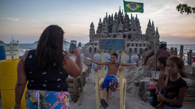 People take photos in front of a castle made by Marcio. The mayor’s office never gave him a problem, he said. “I became a tourist attraction in some way, and also a social service,” he said, gesturing to his bookstand on the nearby promenade. He doesn’t ask for money, only that people exchange what they take. (Mauro Pimentel / AFP) People take photos in front of a castle made by Marcio. The mayor’s office never gave him a problem, he said. “I became a tourist attraction in some way, and also a social service,” he said, gesturing to his bookstand on the nearby promenade. He doesn’t ask for money, only that people exchange what they take. (Mauro Pimentel / AFP)