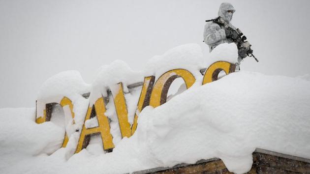 An armed security personnel wearing camouflage clothing stands on the rooftop of a hotel, next to letters covered in snow reading "Davos", near the Congress Centre ahead of the opening of the 2018 World Economic Forum (WEF) annual summit on January 22, 2018 in Davos.(AFP Photo)