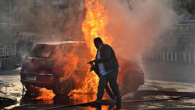 A firefighter tries to douse flames after Karni Sena activists torched a car during a demonstration against the release of 'Padmaavat' in Bhopal.(PTI Photo)