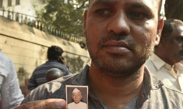 Narendra Patil, son of Dhule farmer Dharma Patil who died at JJ hospital on Sundayt a week after consuming poison at Mantralaya, sits in protest outside the hospital and shows his father’s photo.(Anshuman Poyrekar/HT Photo)