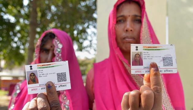 Voters display their Aadhaar cards and finger marked with indelible ink after casting their vote during Ajmer by-election on Monday.(PTI Photo)
