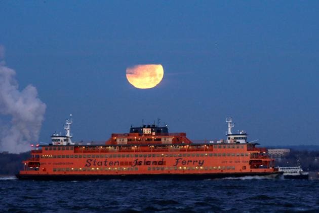 The "Super Blue Blood Moon" sets behind the Staten Island Ferry, seen from Brooklyn, New York, January 31, 2018.(REUTERS)