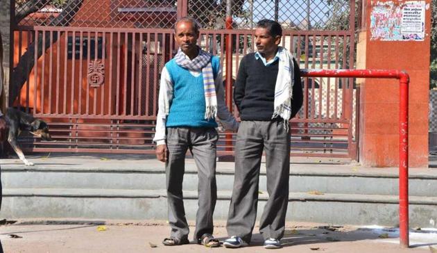Labourers Hariom(in blue pullover) and Avdhesh wait in search of work.(HT Photo)