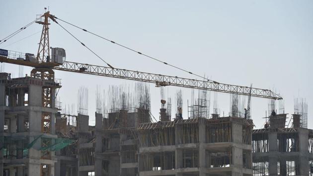 A crane carries construction material to workers atop a building under construction, in Bengaluru.(AFP File Photo)