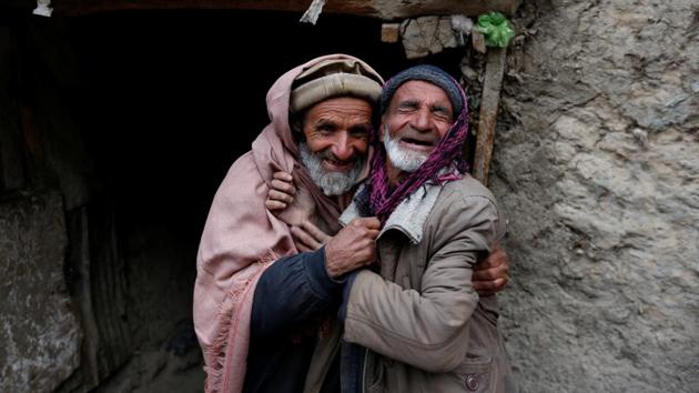 Two friends and traders, Mirza (right), 65, and Noor Mohammad, 72, pose for a picture at the Ka Faroshi bird market in Kabul. (Mohammad Ismail / REUTERS)