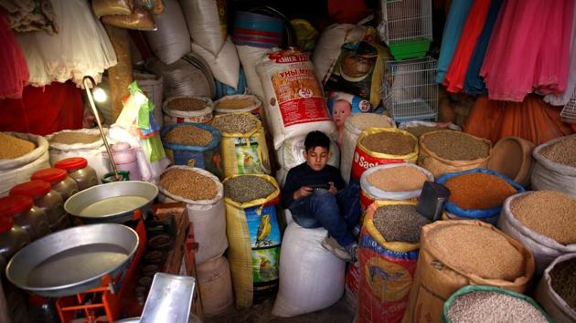 Afshin, 12, plays on a mobile phone inside the shop where he sells bird food at the Ka Faroshi bird market in Kabul. (Mohammad Ismail / REUTERS)