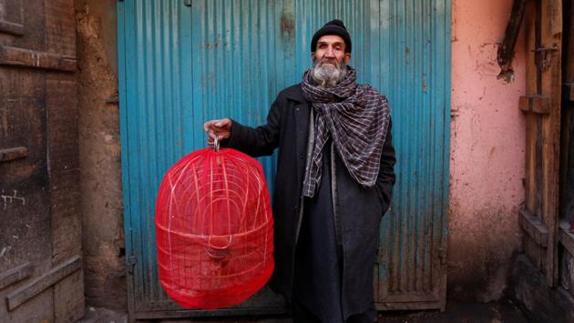 Fatih, 70, holds a cage of partridges as he poses for a picture at Ka Faroshi bird market. An elegant reddish-grey bird with a black band across its eyes and around its throat, a red beak, and black stripes on its side, partridges are bred for fighting. (Mohammad Ismail / REUTERS)