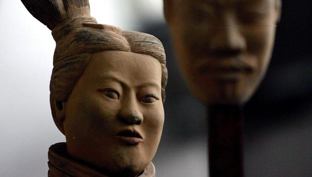 A female Terracotta soldier statue holds the mask of a man as it stands in the midst of a terracotta army made up entirely of women and children at an art gallery in Beijing.(AP File Photo)