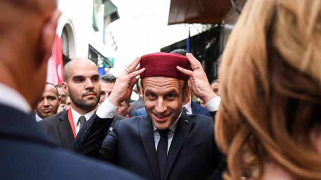 French President Emmanuel Macron (C) tries on a fez during his tour of the Medina (old town) of the Tunisian capital Tunis on February 1, 2018, during Macron's first state visit to the North African country. (Eric Feferberg / AFP) French President Emmanuel Macron (C) tries on a fez during his tour of the Medina (old town) of the Tunisian capital Tunis on February 1, 2018, during Macron's first state visit to the North African country. (Eric Feferberg / AFP)
