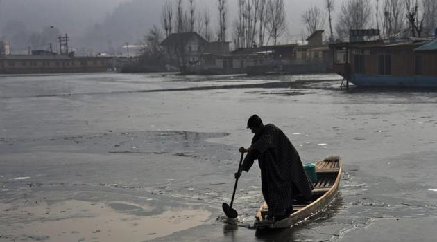 A boatman rows his boat on a partially frozen area of the Dal Lake on a cold winter morning in Srinagar. Temperatures in Kashmir continued to dip on Saturday.(PTI)