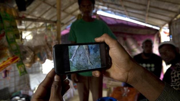 In this Jan. 14, 2018 photo, Rohingya Muslim refugee Mohammad Karim, 26, shows a mobile video of Gu Dar Pyin's massacre inside his kiosk in Kutupalong refugee camp, Bangladesh. (AP) In this Jan. 14, 2018 photo, Rohingya Muslim refugee Mohammad Karim, 26, shows a mobile video of Gu Dar Pyin's massacre inside his kiosk in Kutupalong refugee camp, Bangladesh. (AP)