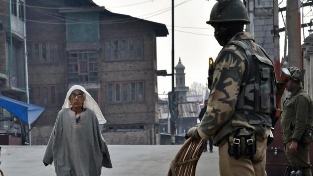 Women walk past a CRPF personnel in Srinagar on Friday.(PTI Photo)