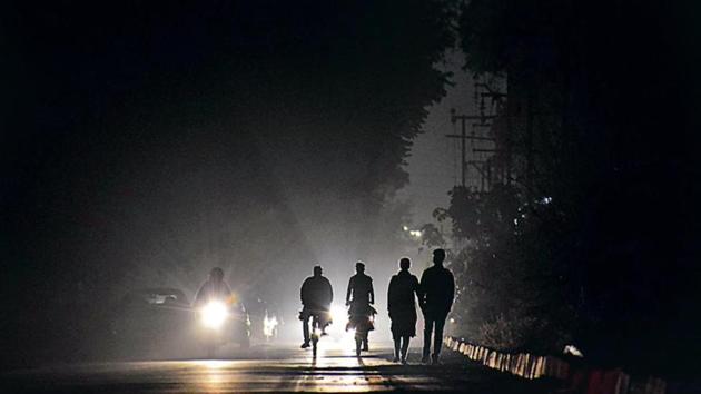 Commuters moving in pitch dark in the absence of functional streetlights at a service lane in Sector 43 in Chandigarh.(Sikander Singh/HT)