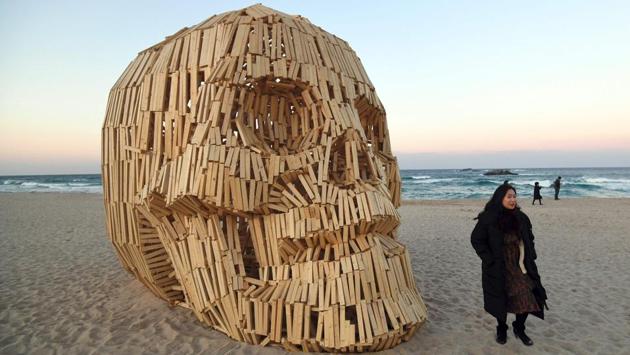 A woman walks past an art work installation of a large wooden skull at Gyeongpo beach. (Jung Yeon-Je / AFP) A woman walks past an art work installation of a large wooden skull at Gyeongpo beach. (Jung Yeon-Je / AFP)