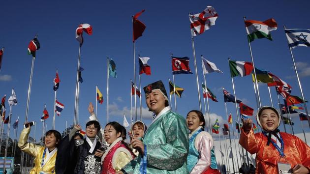 A group of volunteers wearing handboks the Korean traditional dress, greet athletes entering the Olympic Village as flags including North Korea's, fly prior to the Winter Olympics in Gangneung. (Jae C. Hong / AP) A group of volunteers wearing handboks the Korean traditional dress, greet athletes entering the Olympic Village as flags including North Korea's, fly prior to the Winter Olympics in Gangneung. (Jae C. Hong / AP)