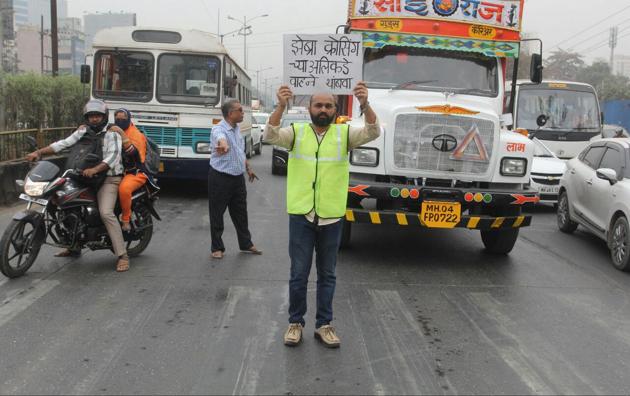 Girish Patil displays a placard at the Anandnagar signal along the Ghodbunder Road.(Praful Gangurde)