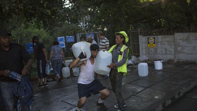 Two men help each other carry water at a natural spring water source in Cape Town. With seasonal rainfall expected to start around May and likely to be low, municipal officials say city residents must stick to regulations requiring them to use fewer than 50 liters per person daily or risk tap closure. (Bram Janssen / AP) Two men help each other carry water at a natural spring water source in Cape Town. With seasonal rainfall expected to start around May and likely to be low, municipal officials say city residents must stick to regulations requiring them to use fewer than 50 liters per person daily or risk tap closure. (Bram Janssen / AP)