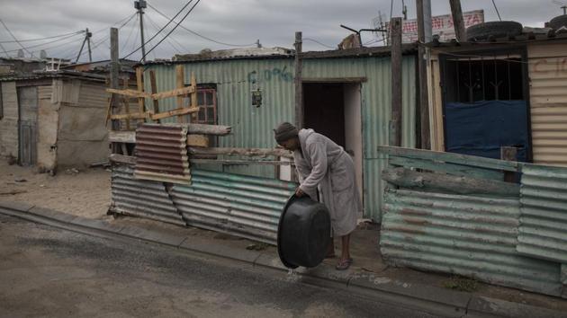 A woman throws away used water at an informal settlement near Cape Town. The one million people in Cape Town’s poor townships make up 25 percent of the city’s 4 million people yet only use 4.5 percent of the water, say water experts. (Bram Janssen / AP) A woman throws away used water at an informal settlement near Cape Town. The one million people in Cape Town’s poor townships make up 25 percent of the city’s 4 million people yet only use 4.5 percent of the water, say water experts. (Bram Janssen / AP)