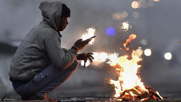 A man warms his hands around a bonfire on a cold winter morning in New Delhi. (PTI File Photo) A man warms his hands around a bonfire on a cold winter morning in New Delhi. (PTI File Photo)