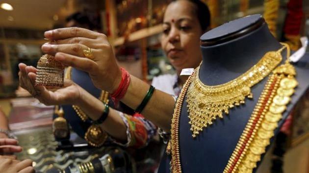 A saleswoman shows a gold earring to customers at a jewellery showroom in Mumbai. (Reuters) A saleswoman shows a gold earring to customers at a jewellery showroom in Mumbai. (Reuters)