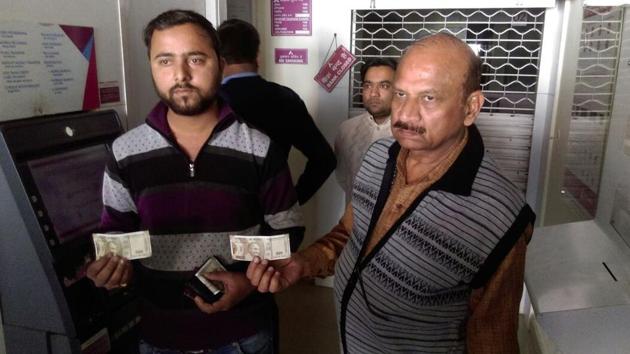 Himanshu Tripathi and Ramendra Awasthi, who work for local marble dealers, show the fake Rs 500 notes withdrawn from the ATM at Marble Market in Kanpur’s Kidwai Nagar.(HT PHOTO)
