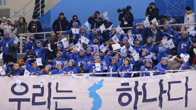 Ice Hockey – Pyeongchang 2018 Winter Olympics – Women Preliminary Round Match - Sweden v Korea - Kwandong Hockey Centre, Gangneung, South Korea – February 12, 2018 - Fans wave Korea Unification flags behind a banner that reads "We are one". (REUTERS) Ice Hockey – Pyeongchang 2018 Winter Olympics – Women Preliminary Round Match - Sweden v Korea - Kwandong Hockey Centre, Gangneung, South Korea – February 12, 2018 - Fans wave Korea Unification flags behind a banner that reads "We are one". (REUTERS)