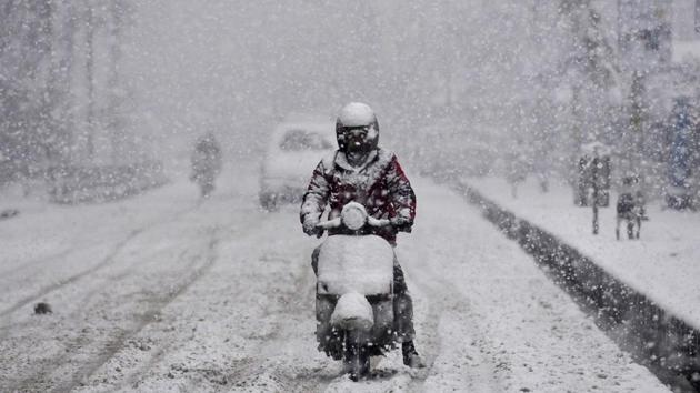 A man rides a scooter in Srinagar as it snows on Monday. (Waseem Andrabi /HT Photo)
