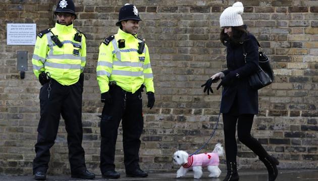 A woman walks her dog past police officers outside Stamford Bridge stadium in London in December 2017. To visitors, it is something of a surprise to see policemen smiling and having relaxed conversation with tourists and onlookers (AFP) A woman walks her dog past police officers outside Stamford Bridge stadium in London in December 2017. To visitors, it is something of a surprise to see policemen smiling and having relaxed conversation with tourists and onlookers (AFP)
