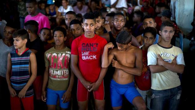 Young wrestlers stand still during a priest’s prayer at the start of a championship coined “The truth of my neighbourhood,” in the Chicharrones neighbourhood of Santiago, Cuba. In this neighbourhood, a wrestling-loving local man created a homegrown, neighborhood-backed program to support aspiring wrestlers from Cuba's economically struggling provinces. (Ramon Espinosa / AP)
