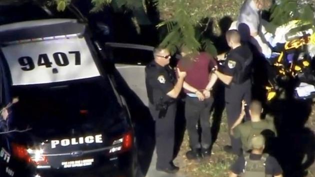 A man placed in handcuffs is led by police near Marjory Stoneman Douglas High School in a still image from video. Most of the victims were shot inside the school building. Two were killed outside and one further away as the assailant tried to flee. The gunman was arrested not too far from the school and was said to be cooperating with investigators. (WSVN.com via REUTERS) 