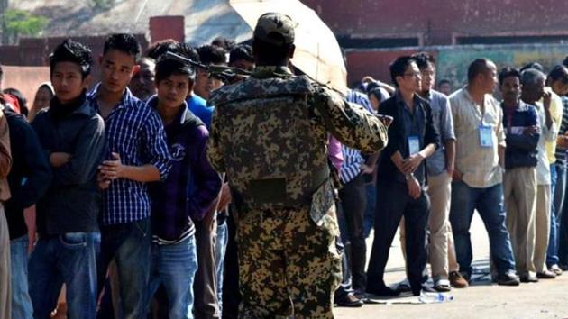 A file photo of a security officer walking past voters standing in queue at a polling station in Dimapur. (AFP Photo) A file photo of a security officer walking past voters standing in queue at a polling station in Dimapur. (AFP Photo)