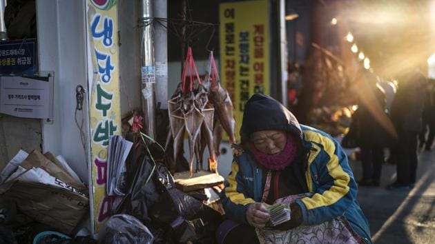 A woman selling dried fish runs through a wad of money as she waits for customers. The only effect of the Winter Olympics has been a volunteer information tent and a glossy map book to help foreign tourists navigate the alleys and by-lanes. Few people in the region speak English and the government had to specially train speakers ahead of the games. (Felipe Dana / AP) A woman selling dried fish runs through a wad of money as she waits for customers. The only effect of the Winter Olympics has been a volunteer information tent and a glossy map book to help foreign tourists navigate the alleys and by-lanes. Few people in the region speak English and the government had to specially train speakers ahead of the games. (Felipe Dana / AP)