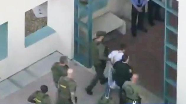Police escort a suspect into the Broward Jail after checking him at the hospital following the shooting at Marjory Stoneman Douglas High School in Parkland. “We already began to dissect his websites and the things on social media that he was on and some of the things that came to mind are very, very disturbing,” Broward County Sheriff Scott Israel told reporters. (WSVN.com via REUTERS) 