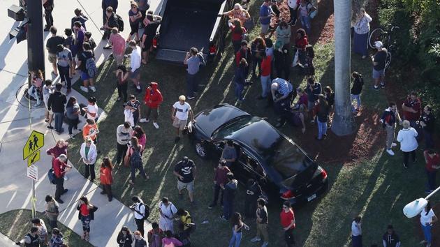 People wait for loved ones as they are brought out of the Marjory Stoneman Douglas High School after a shooting at the school on February 14, 2018 in Parkland, Florida. A 19-year-old former student gunned down at least 17 people, including students and staff, and injured 15 in a Florida high school on Wednesday afternoon. (Joe Readle / Gety Images / AFP) 