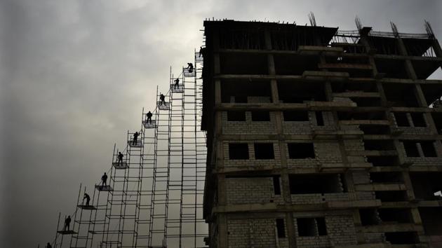 Labourers stand on a scaffolding shift of an under construction building in Greater Noida on February 12. (R S Iyer / AP) Labourers stand on a scaffolding shift of an under construction building in Greater Noida on February 12. (R S Iyer / AP)