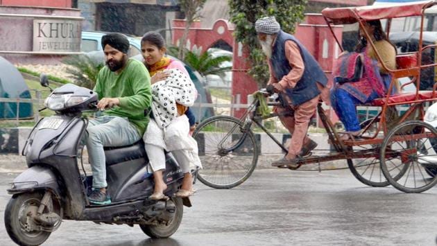 Commuters bear the rain in Amritsar on Saturday. (Sameer Sehgal/ht)