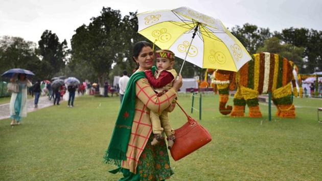 Visitors at the Rose Festival take cover under their umbrellas during rain in Chandigarh on Saturday. (karun sharma/ht)